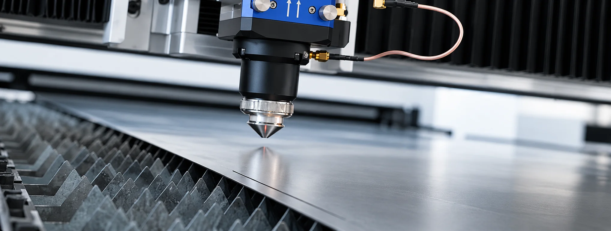 Cabeçote de corte da fiber laser sobre a chapa de aço, com a grade de apoio da mesa em primeiro plano